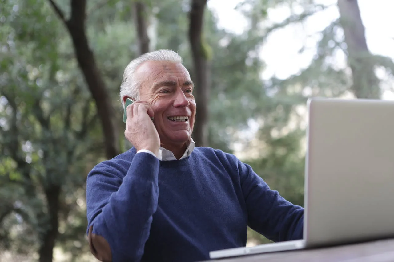 A patient smiling while speaking with our office by phone