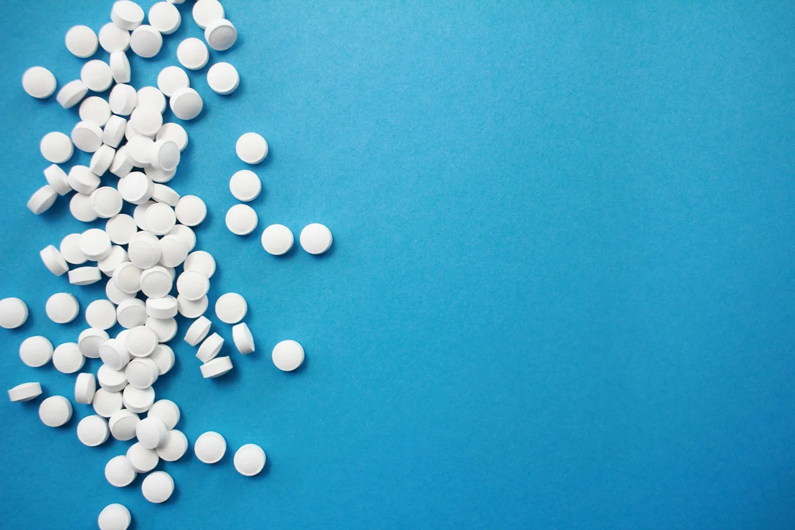 White tablets scattered on a bright blue background