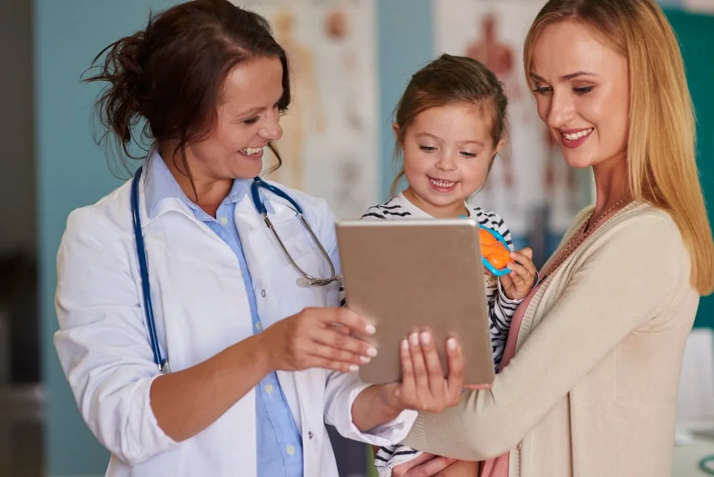A physician reviewing a health record together with a mother and daughter
