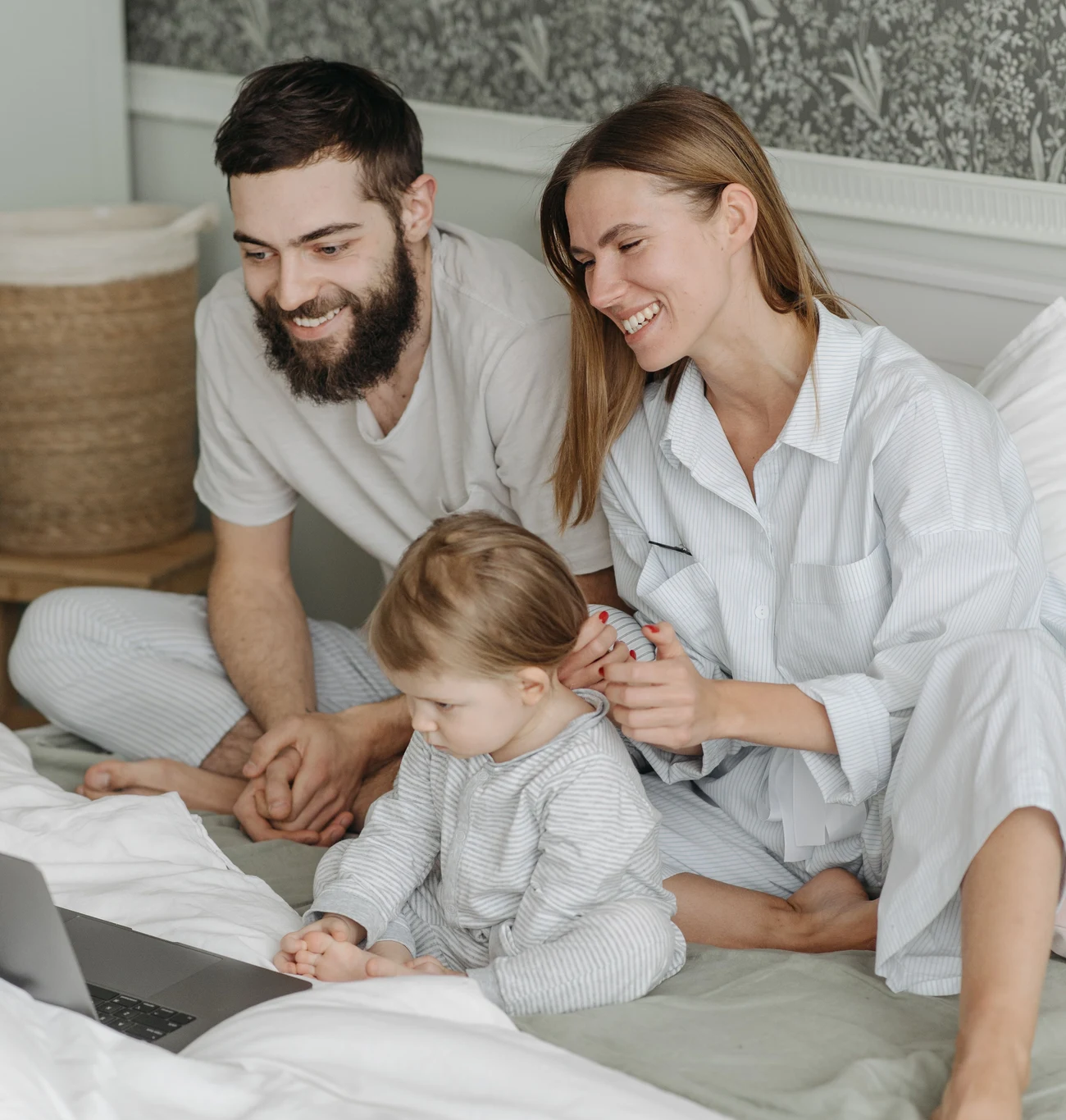 A young family smiling together while looking at a laptop screen