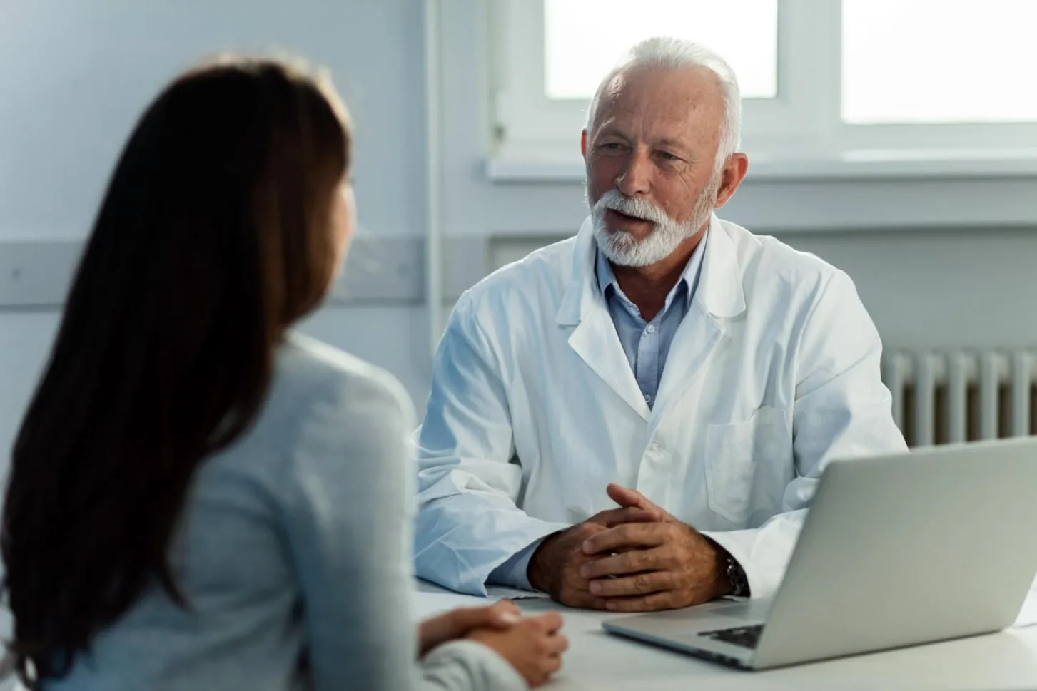 A physician reviewing a patient's health history together at a laptop