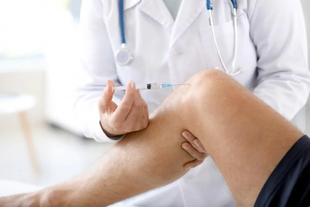 A physician administering a joint injection into a patient's knee