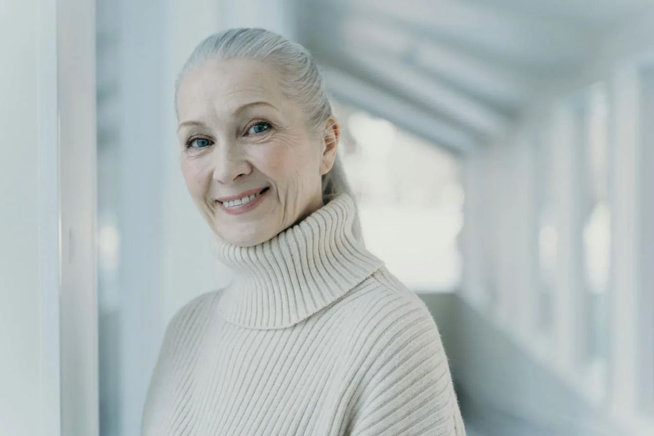 A smiling woman with gray hair in a cream sweater, representing patients who feel like themselves again