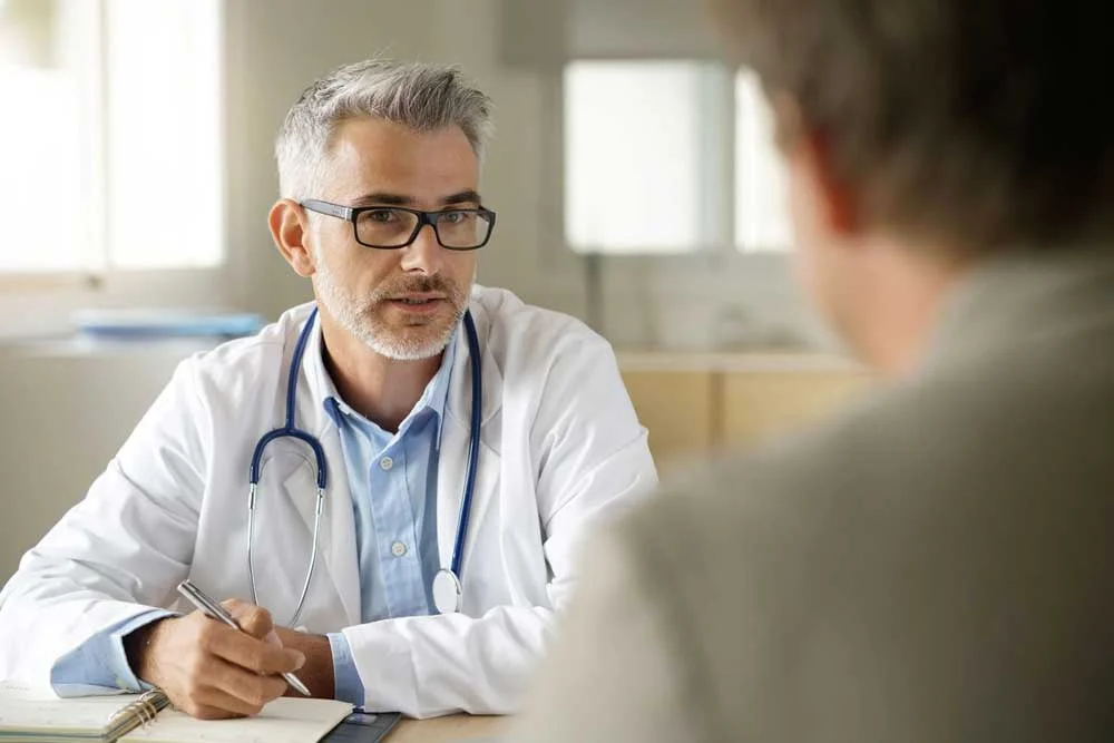 A clinician at his desk reviewing a patient's cholesterol and lipid panel results during an office visit