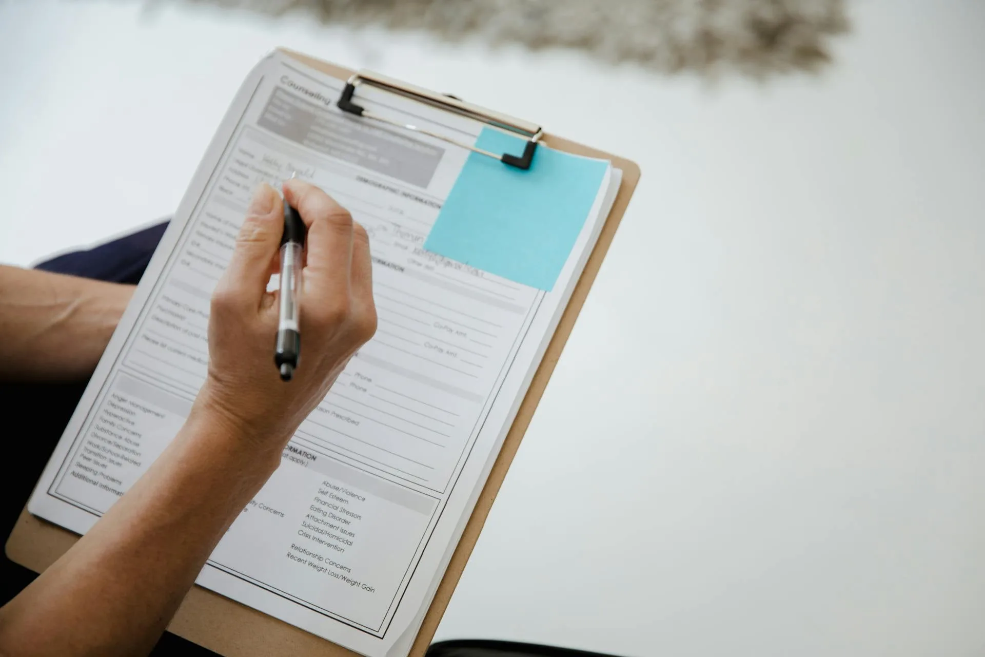 A patient filling out an intake form on a clipboard