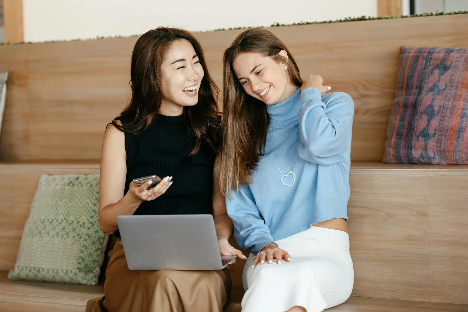 Two patients smiling while looking at a laptop together, illustrative of staying connected to your care after your visit