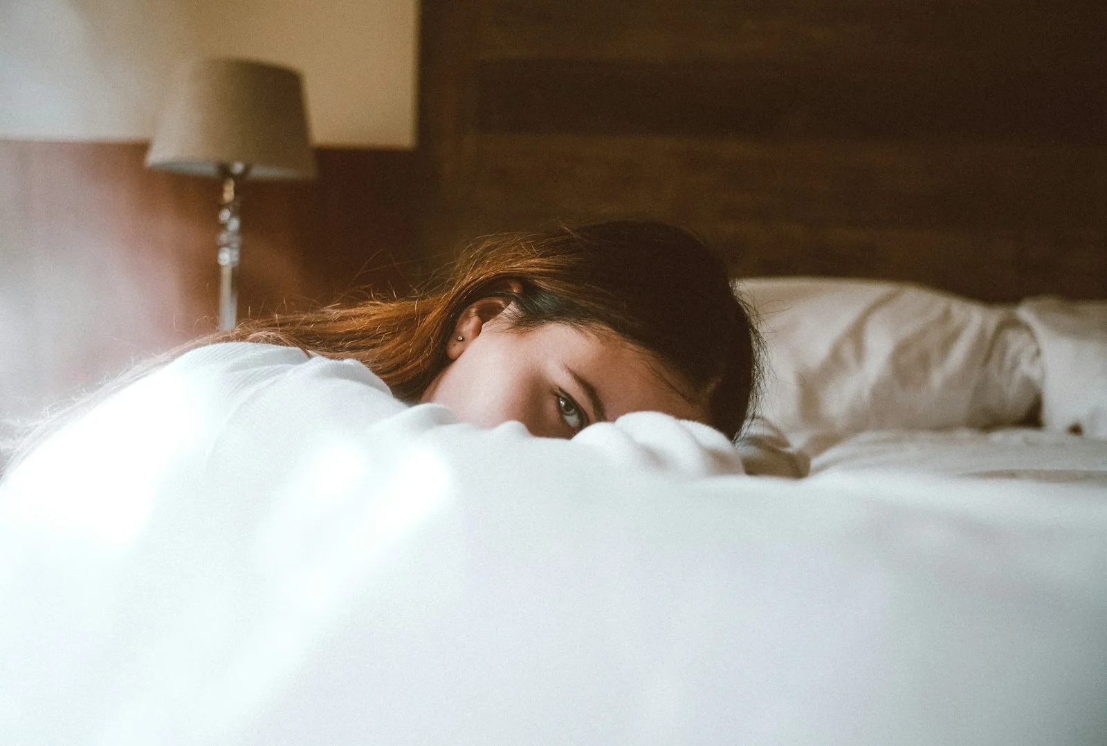 A tired woman resting her head on her bed