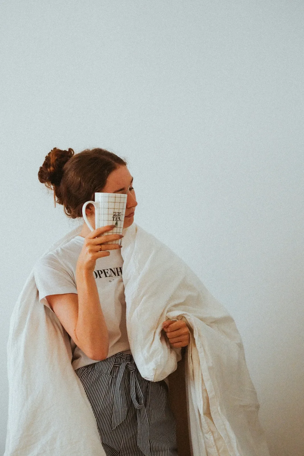 A woman in a white robe holding a mug of coffee in the morning
