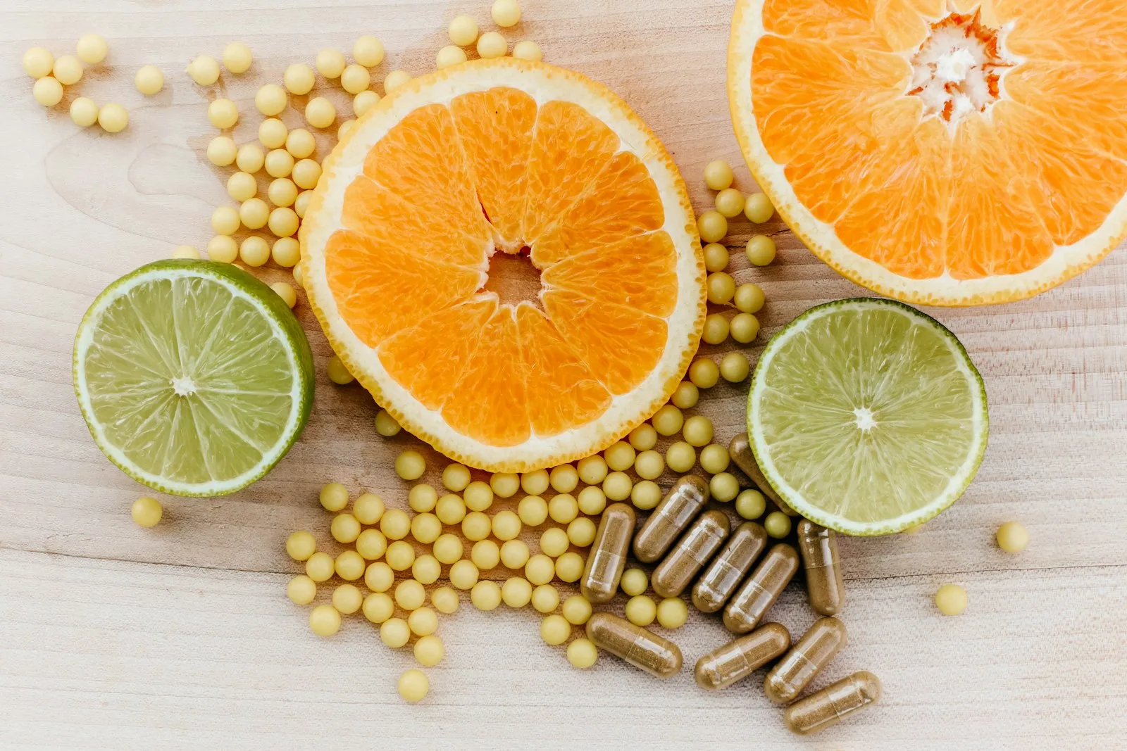 Citrus slices, soy beads and supplement capsules on a wooden surface