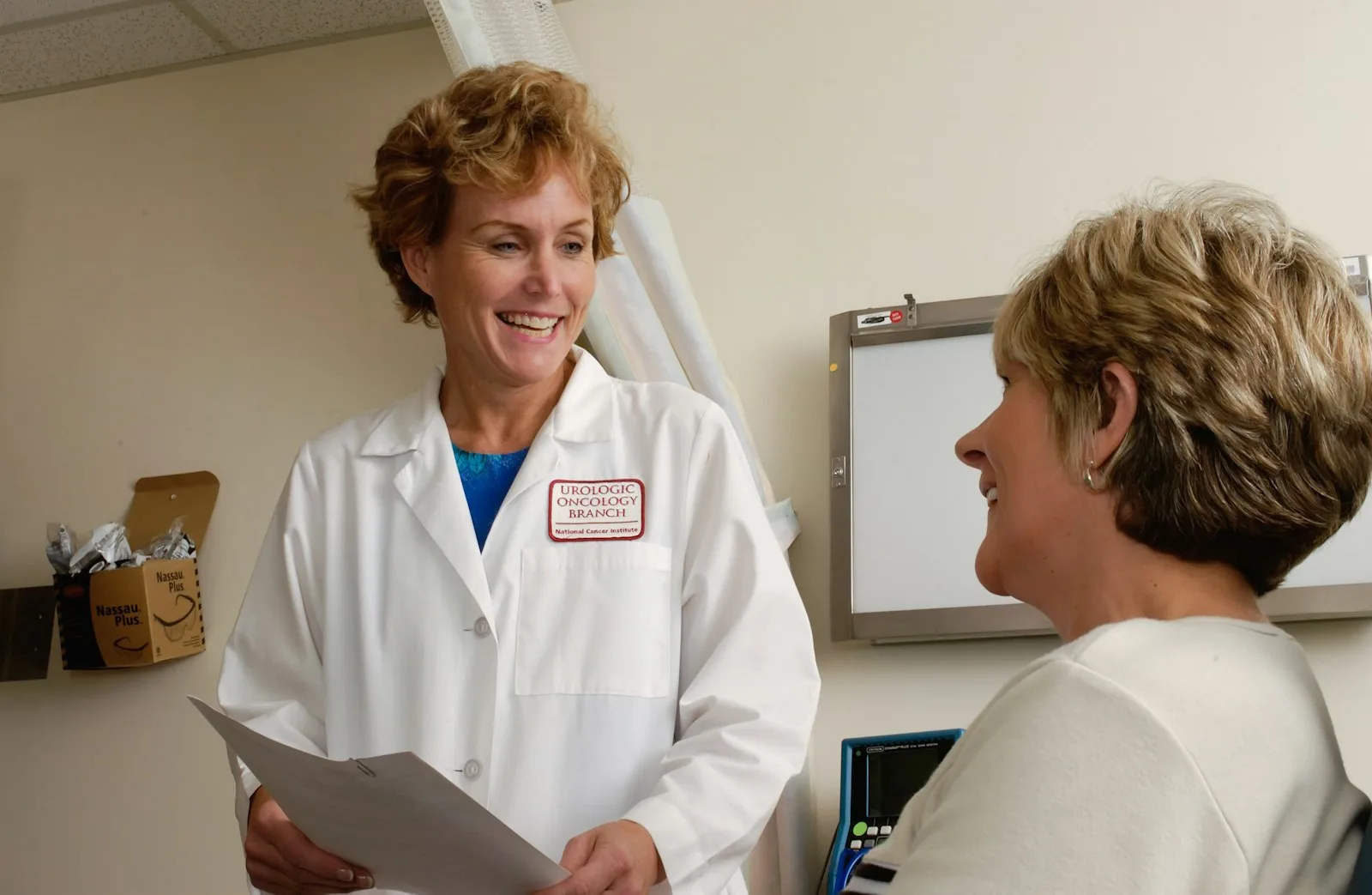 A smiling clinician in a white coat going over results with a patient