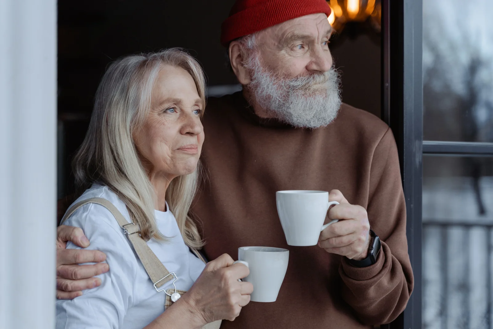 An older couple holding coffee mugs together, representative of the long-term relationship an annual physical helps maintain