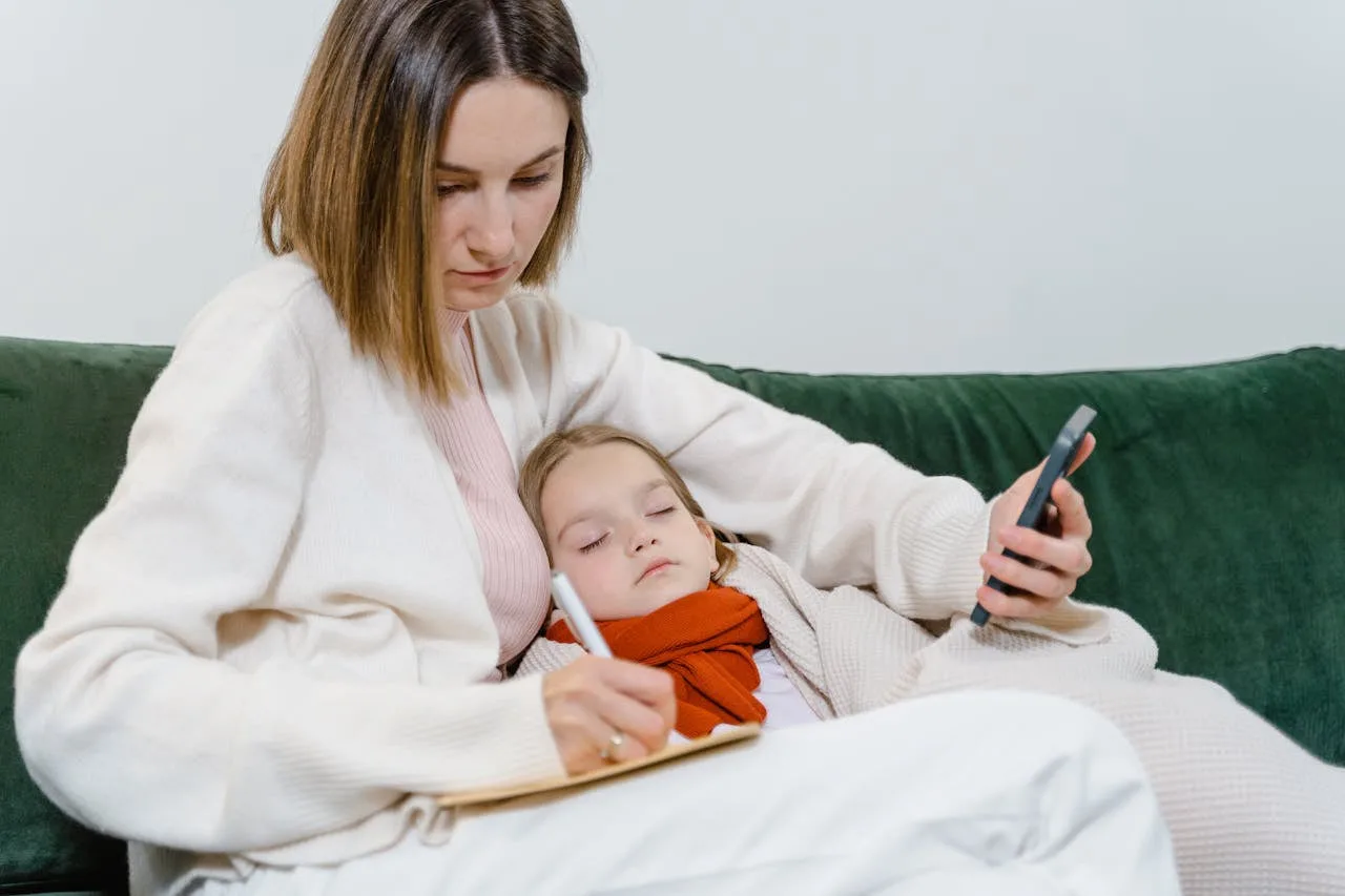 A parent caring for a sick child at home while preparing for a telemedicine appointment