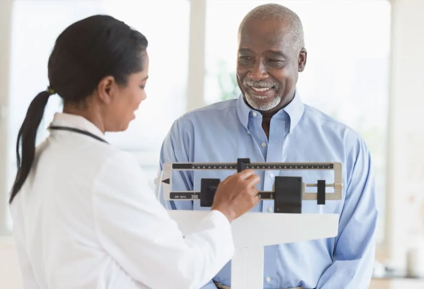 A physician checking a patient's weight during a medical weight-management visit